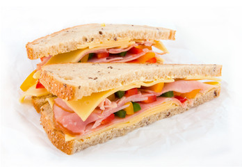 Sandwich with ham, cheese and vegetables on the paper