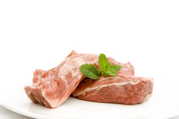 Raw neck of lamb on a white plate garnished with mint