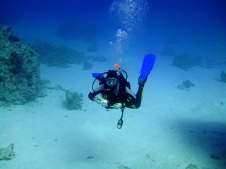 Diver with camera in deep and bubbles. Underwater photographer