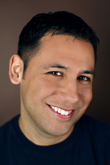 Portrait of a young hispanic man smiling on a brown background