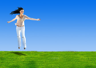 Woman jumping on a hill of green grass