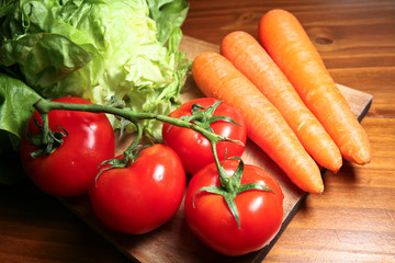 Légumes : tomates, carottes et salades sur planche de bois