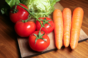 Légumes : tomates, carottes et salades sur planche de bois