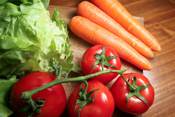Légumes : tomates, carottes et salades sur planche de bois