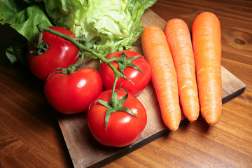 Légumes : tomates, carottes et salades sur planche de bois