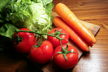 Légumes : tomates, carottes et salades sur planche de bois
