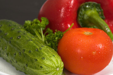 Fresh vegetables on a white plate and a black background