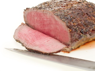 ganzes Roastbeef und eine geschnittene Scheibe, freigestellt auf weißem Hintergrund