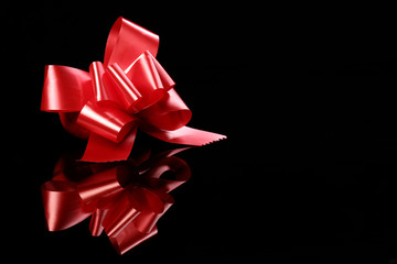 red bow standing on a black with reflections2.