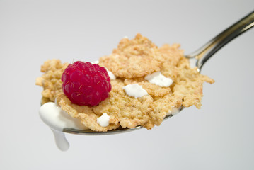 Cereal flakes on spoon with milk and raspberry