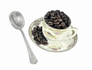 Coffee beans in and antique cup and saucer.