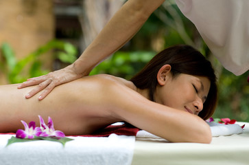 A young woman having a back massage outside in tropical setting