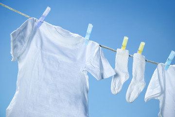 Eco friendly  laundry drying on clothes line against a blue sky  - obrazy, fototapety, plakaty