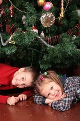 two children under christmas tree