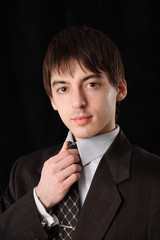 Man in suit corrects tie