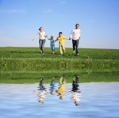 family of four running grass sky water