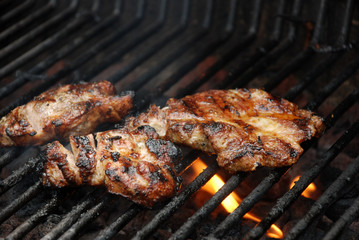 Meat cooking on barbecue grill with flames