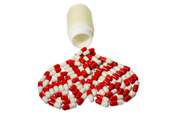 red and white capsules in the form heart, spilting from bottle.