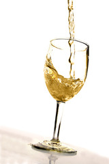 White wine being poured into a glass on white