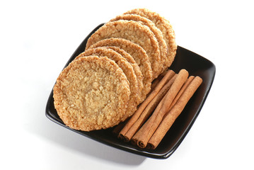 Cookies and cinnamon sticks on a black plate