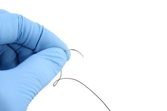 gloved hand holding suture needle