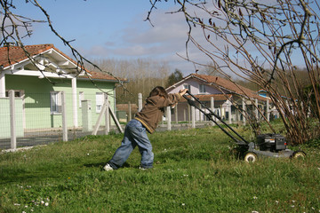 petit garçon entrain de tondre la pelouse avec une tondeuse