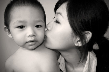 young mother kissing son - in sepia tone