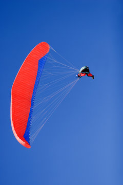 a paraplane flying high up in the deep blue sky