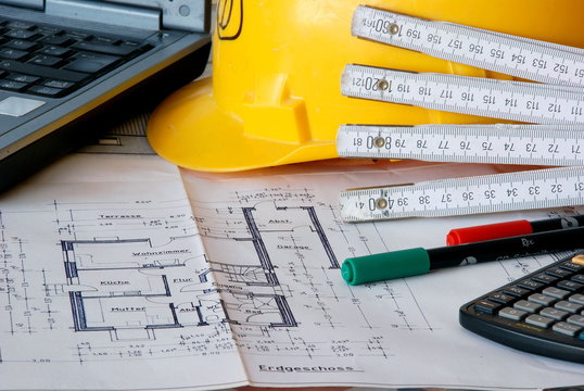Bauzeichnung mit Notebook und Bauhelm