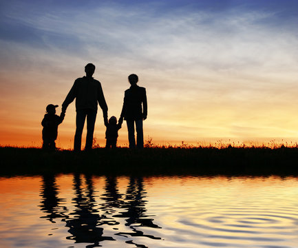 family of four on sunset sky, water