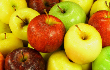 Different sorts apples covered with water drops on market.