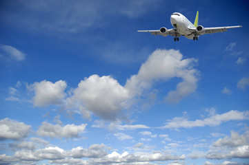 Fototapeta na wymiar Podróże lotnicze - Samolot latający w błękitne niebo z chmurami