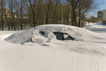 Car covered with snow in winter blizzard snowdrift