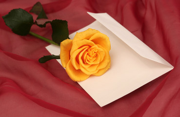 Yellow rose and envelope on a red background
