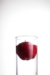 A red delicious apple floating in a glass of water