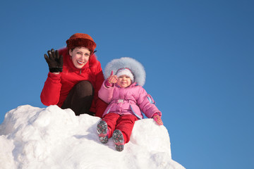 mother with child sit on snow hill
