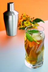 Glass of ice tea and on background of cocktail shaker