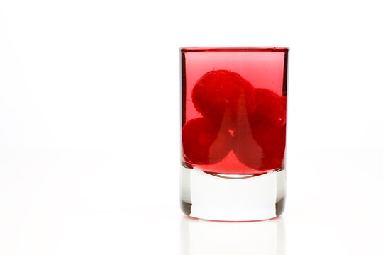 Schnaps in Glas mit Himbeeren