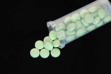 green pills in dispenser,black background