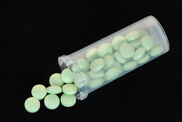 green pills in a plastic dispenser on a black background 