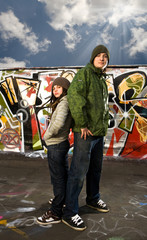 Young boy ang girl stand back to back on a graffity background