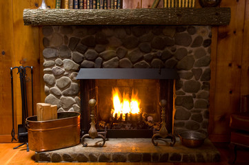 Fototapety  close-up of stone fireplace in log cabin with blazing fire