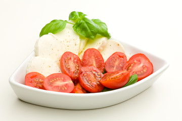 Weiße Schale mit Mozzarella, Tomaten und Basilikum