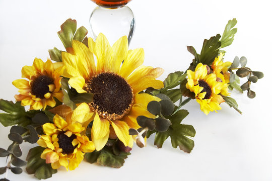 Big yellow wineglass with bouquet of artificial sunflower