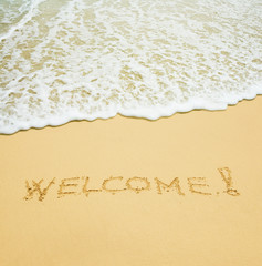 welcome written in a sandy tropical beach