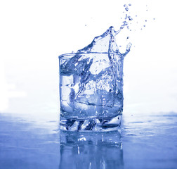 Glass of splashing water with ice