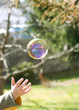 Child hand and big soap bubble