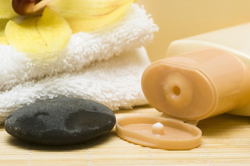 Yellow bottle of shampoo with towel and orchid