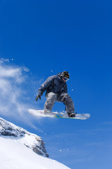 Male snowboarder jumping of a hill