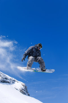 Male snowboarder jumping of a hill